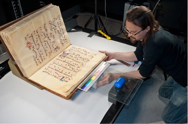 staff arranging a medieval book with a color calibration grid