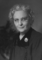 Photograph of Mary Ely Lyman, a light-haired woman in glasses and dark outfit with a brooch