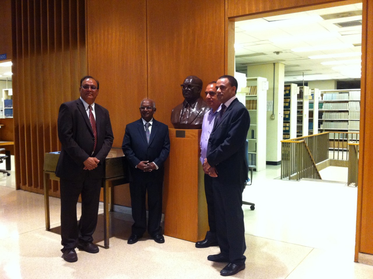 A side view of the bust with two men posing on each side.