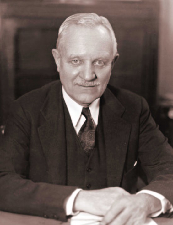 black and white portrait photo of Frederick Keppel sitting at a desk in a suit