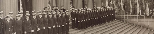 Navy midshipmen in front of Low Library surrounded by flags and banners